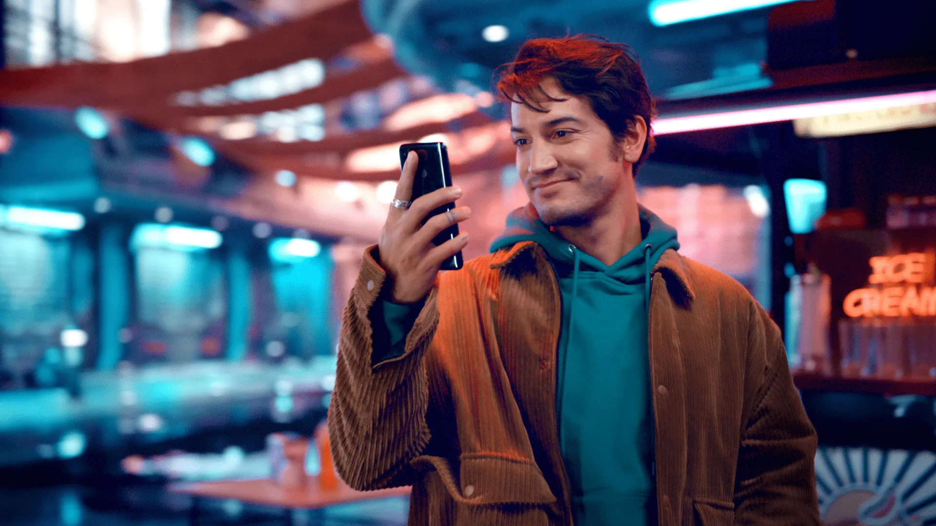 A man happily looking at his phone with a colorful and vibrant background